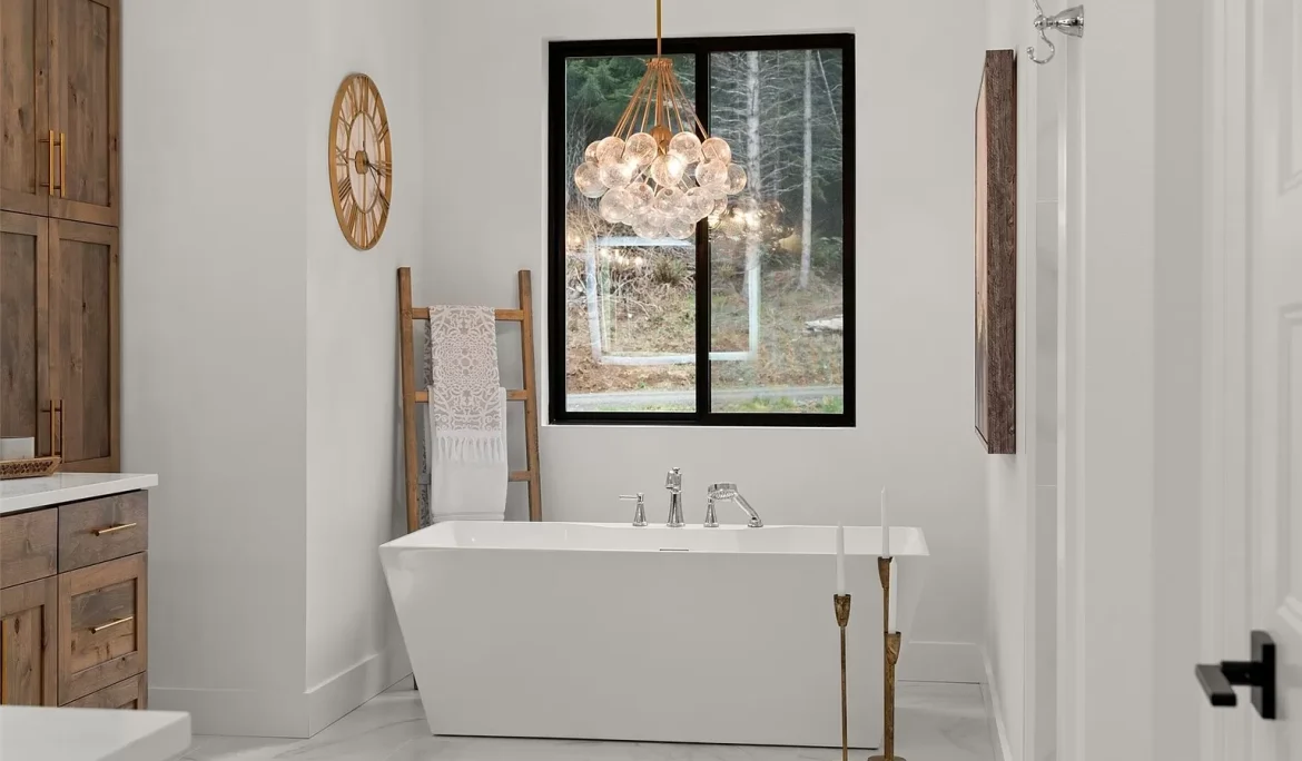 Freestanding soaking tub beneath a window with modern pendant lighting and neutral finishes