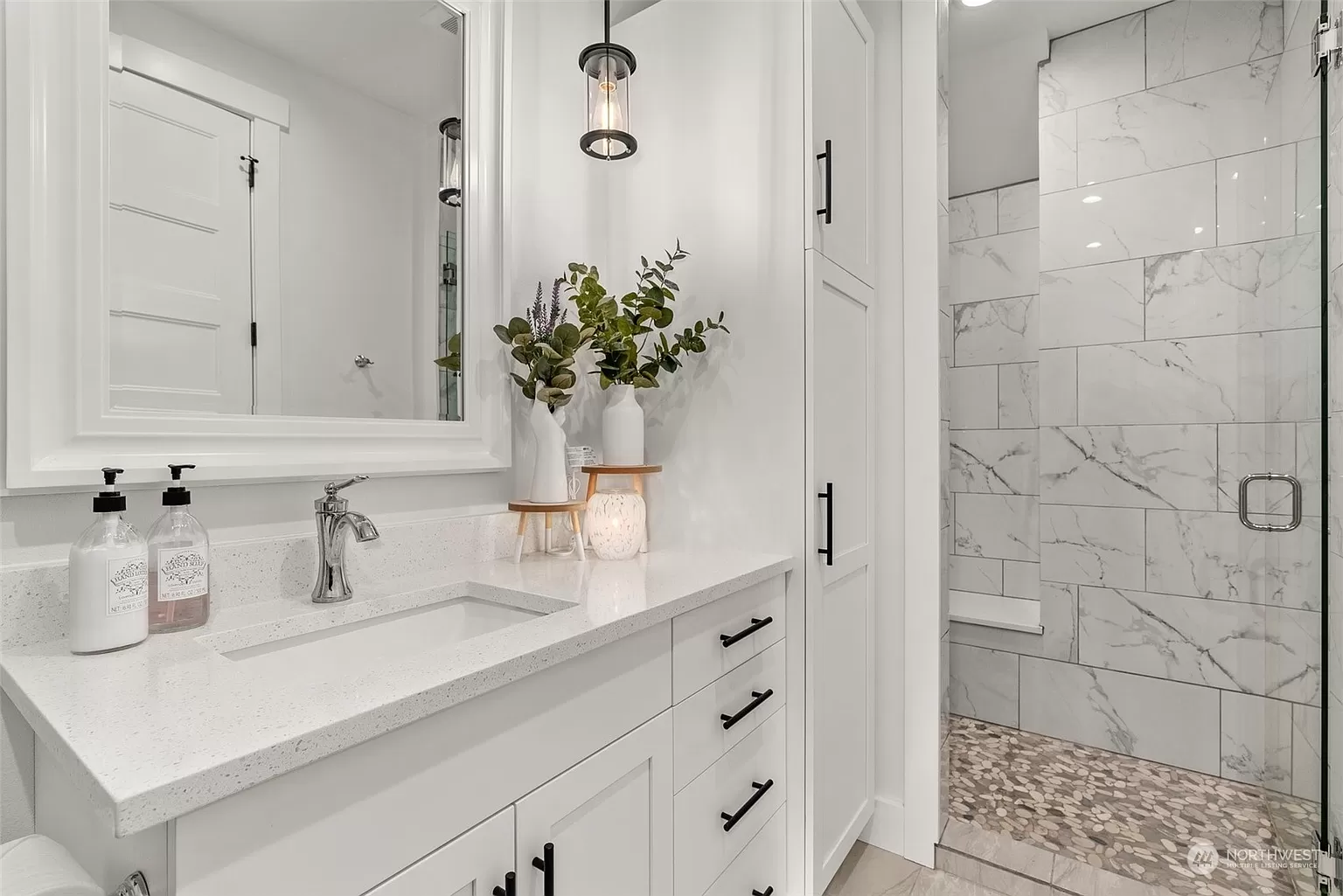 Bright bathroom with white vanity, quartz countertop, black hardware, and walk-in tiled shower