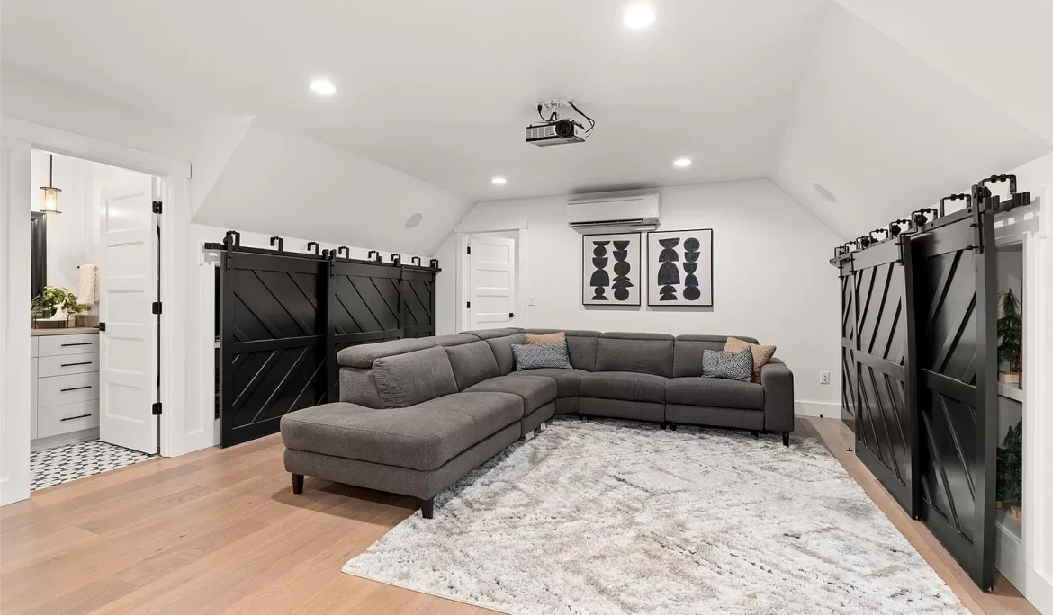 Entertainment room with sectional sofa, projector setup, and sliding barn doors in Olympia, WA home