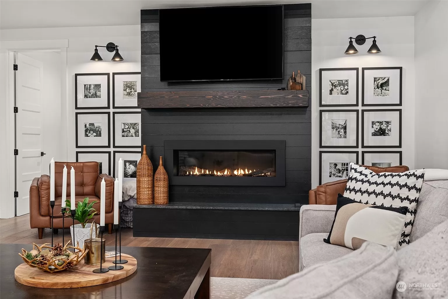 Black fireplace with wood mantel, framed artwork, and modern accent lighting