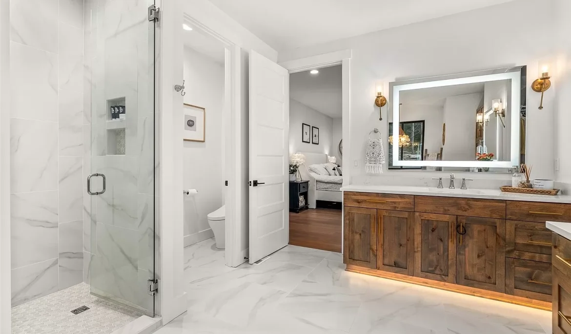 Primary bathroom design in Olympia, WA with double wood vanity, marble-look tile, and walk-in shower